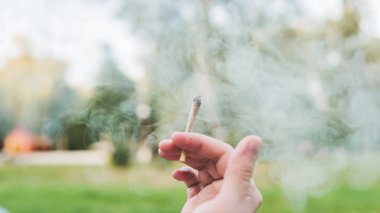 Genç kişi açık havada tıbbi marihuana ortak sigara. Y