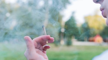 Genç kişi açık havada tıbbi marihuana ortak sigara. Y