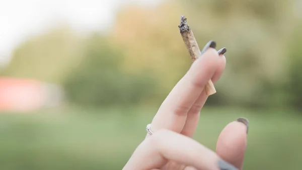 Primer plano de las manos de las mujeres que sostienen la marihuana conjunta, fumar canna —  Fotos de Stock