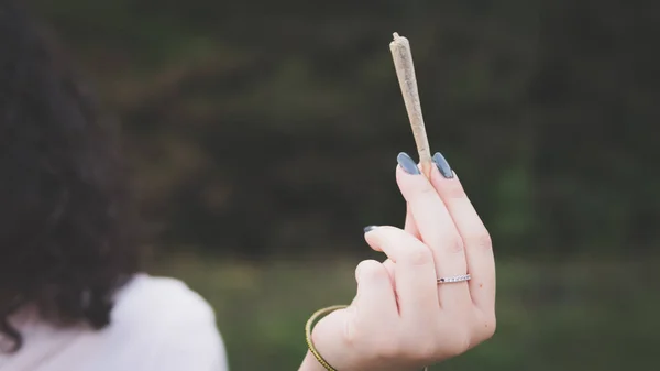 Gros plan des mains féminines tenant un joint de marijuana, fumant de la canna — Photo