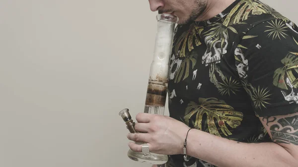 The young person smoking medical marijuana with bong, indoors. T