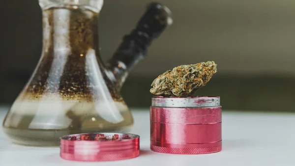 Tıbbi marihuana tomurcuklarıyla birlikte kirli nargile ve öğütücü yakın plan.