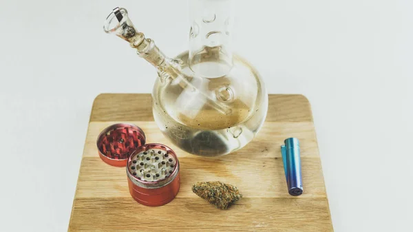 Zbliżenie bonga i szlifierki z leczniczymi pączkami marihuany na — Zdjęcie stockowe