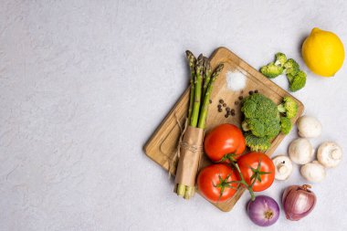 Organik taze sebzeler grubu - yeşil kuşkonmaz, brokoli, gri arka planda mantarlar, düz yatak. Sağlıklı vejetaryen yemek, diyet ve ev yemeği kavramı. Üst görünüm, alanı kopyala.