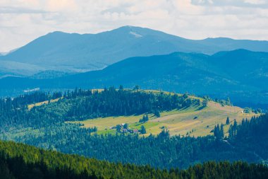 Beyaz bulutlu mavi gökyüzü ile inanılmaz dağ manzarası, Ukrayna 'nın Bukovel Karpatlar şehrinde güneşli bir yaz günü. Doğal dış seyahat geçmişi.