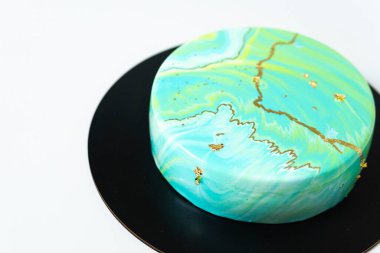 Mavi ve yeşil aynalı kremalı pastaya yakın plan. Fransız tatlısı. Pastanın üzerindeki dondurulmuş ayna kreması. Pişirme ve şekerleme konsepti. Beyaz arkaplan