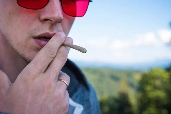 在户外吸食大麻的年轻人的特写镜头血红蛋白在男性手中变钝 大麻是一种草药和替代药物的概念 — 图库照片