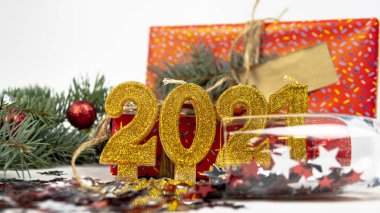 Arka planda altın 2021 sayısının yazılı olduğu tatil arkaplanı, konfeti, hediye kutusu ve Noel ağacı dalı yer alıyor. Mutlu yıllar ve tatil konsepti. Seçici odak.