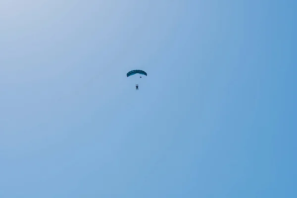 Tandem parachute jump. Silhouette of skydiver flying in blue clear sky. Concepts of extreme sport and adrenaline.