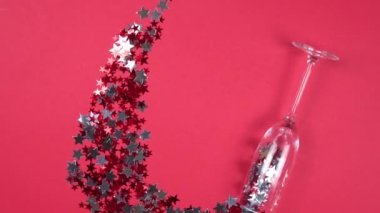 Kırmızı arka planda 360 derecelik konfetili şampanya kadehleri düz yerde. Tebrik kartı kavramları, yeni yıl arifesi ve gece yarısı. Üst görünüm.