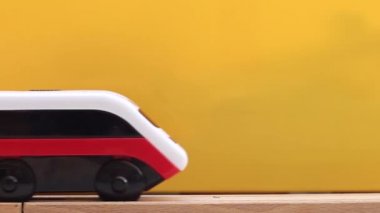 Tahta oyuncak tren hareket ediyor, arabalarıyla. Sarı arkaplan