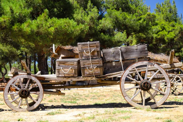An old covered wagon wheel.Traditional wooden tumbrel, wooden crates loaded