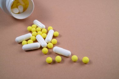 Karışık hapları beyaz şişeden döktüm. İlaç tıp tablet, kapsül ve kahverengi zemin hapları