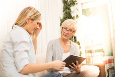 Orta yaşlı bir kadın, bir tablet bilgisayarda genç ve güzel bir kız programının başvurusunu gösterir..