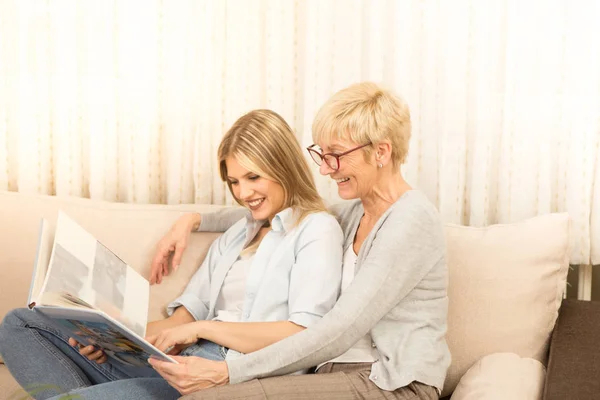 The beautiful mom and daughter watch the family album, and remember the beautiful moments.