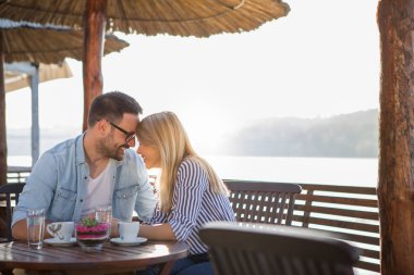 Güzel bir genç çift su kenarında bir restoranda oturuyor ve aşk duygularını paylaşıyor..