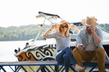 Güzel sarışın ve yakışıklı genç adam rıhtımda otur ve nehirde harika anlar geçir..