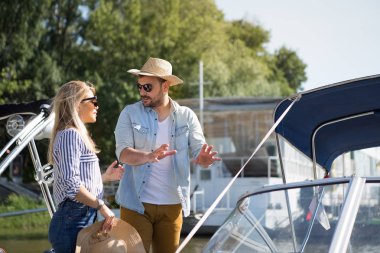 They're on the dock, a handsome young man explains to the beautiful blonde how to drive a speedboat.