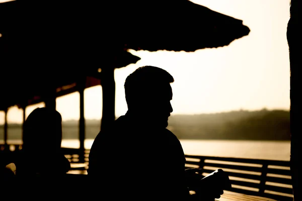 He and his girlfriend sitting in a cafe on the sea and watching the sunrise.