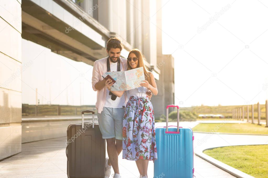 A beautiful young girl and her boyfriend are waiting to board the plane and they are looking at the map of the tourist destinations they want to visit.