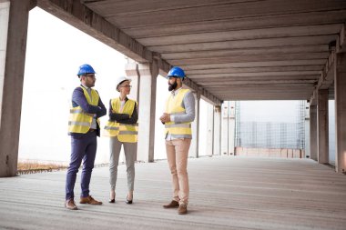 Genç mimar muadilleriyle birlikte bir şantiyede ve bina için bazı yeni fikirler sunuyor..