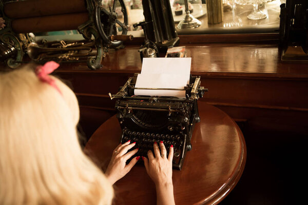 A journalist writes on a typewriter in the past century.