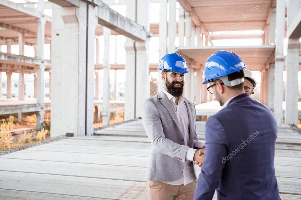 Hipster engineer shakes hands with an investor because they have made very successful co-operation.