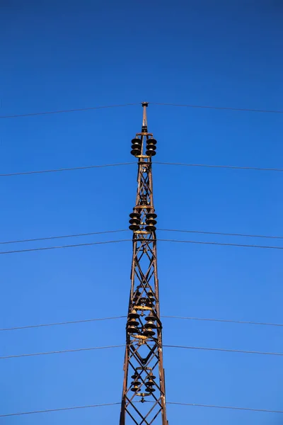 Symmetrical photography of the construction of the transmission line for the transmission of high voltage electricity. Behind is a clear blue sky.