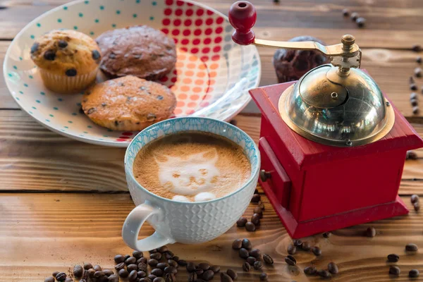 Red coffee mill, cup latte with a painted cat on milk foam and biscuits on a old wooden table. — Stock Photo, Image