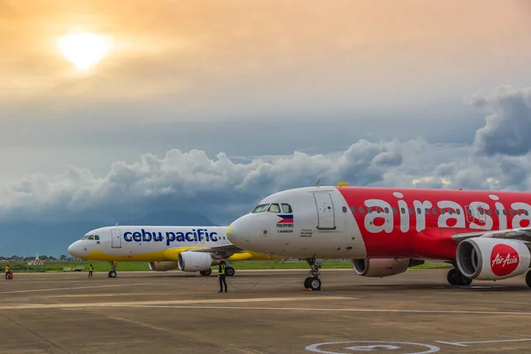 Düşük hava yolları Cebu Pasifik ve Air Asia uçak renkli günbatımında Puerta Princesa Palawan Adası, Filipinler havaalanında, mal.