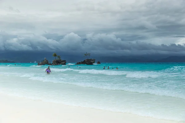 Beyaz Beach Boracay ve insanlar Grotto Willys üzerine Meryem Ana heykeli standları Rock yakınındaki bulutlu bir günde turkuaz masmavi denizde yüzmek. Boracay, Filipinler