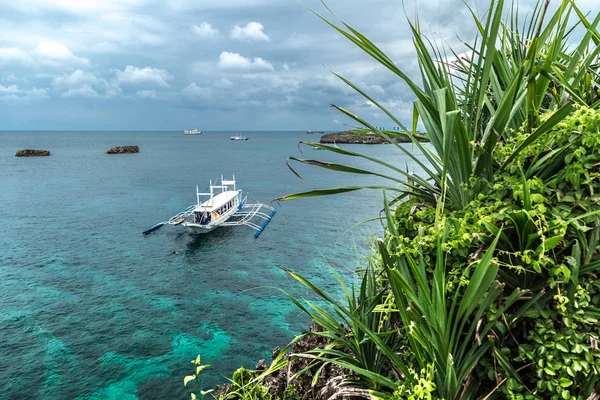 Vista mare azzurro e una barca turistica vicino a piante verdi su Crystal Cove piccola isola vicino all'isola di Boracay nelle Filippine — Foto Stock