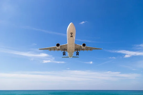 Um avião de passageiros a descolar no céu nublado. Aeronaves voam sobre o mar e a ilha tropical . — Fotografia de Stock