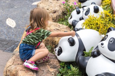 Parkta heykel oyuncak panda ile oynayan sevimli küçük kız. Hong Kong, Çin. Ocak 2018.