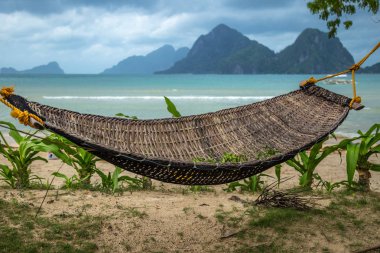 Arka planda tropik ada ile gölgede geleneksel örgülü hamak