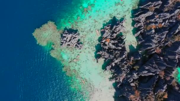 Aerial top view flying amazing rocks and tropical coral reef lagoon. Kayak are sailing on the sea. Coron, Busuanga, Philippines. — Stock Video
