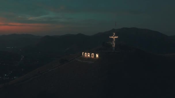 コロン市の夜に大きな発光文字とキリスト教の宗教的な十字架を持つタピア山。2月15日 - 2019年。ブスアンガ島、パラワン、フィリピン. — ストック動画
