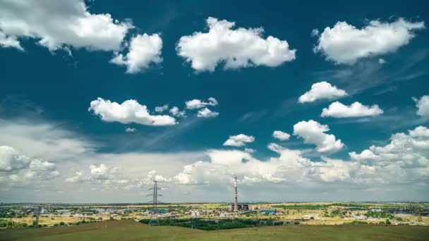Промышленный ландшафт с электростанцией с желтым полем и большими голубыми облаками — стоковое видео