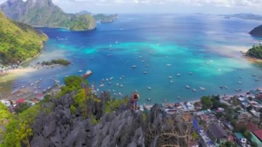 Limana ve mavi deniz lagününe bakan dağın kayalık tepesinde duran turistlerin üzerinde uçmak