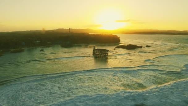 Große Wellen kommen und schöne Sonnenuntergangslandschaft an der hölzernen Brücke auf Wolke 9 Strand, Siargao Insel Philippinen. — Stockvideo