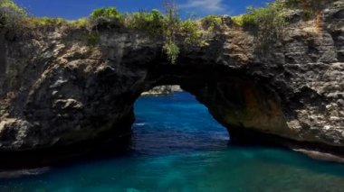 Kaya kıyı şeridi ve taş kemer Endonezya 'da, Nusa Penida' daki gök mavisi deniz üzerinde. Hava görüntüsü 4K
