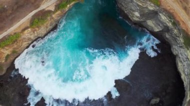 Kaya kıyı şeridi. Denizin üzerinde taş kemer. Kırık plaj, Nusa Penida, Bali, Endonezya. Hava görüntüsü 4K