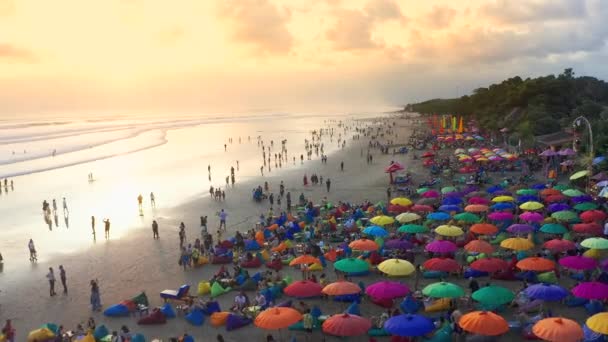 Pessoas sentadas e caminhando na praia e desfrutando da vida de festa em Seminyak Beach ao pôr do sol. 15 de janeiro de 2020: Bali, Indonésia . — Vídeo de Stock