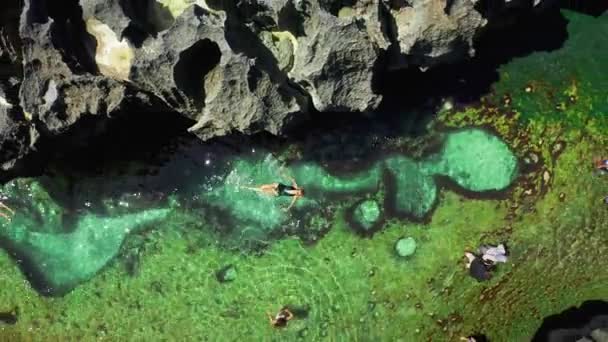 Ung vacker kvinna simmar i en naturlig pool änglar Billabong på Broken Beach i Nusa Penida ön, Bali i Indonesien. Flygvy 4K — Stockvideo