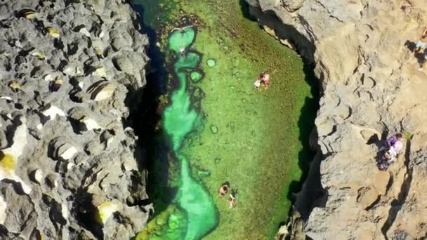 Muitas pessoas viajam na piscina natural e falésias na praia de rock tropical Angels Billabong, Nusa Penida. BAILI, INDONÉSIA - 15 de fevereiro de 2020. Vista aérea 4K — Vídeo de Stock