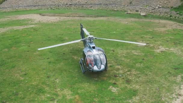 Légi felvétel a helikopter körül, ami a zöld mezőn landolt az utasokkal. Légi felvétel 4K. — Stock videók