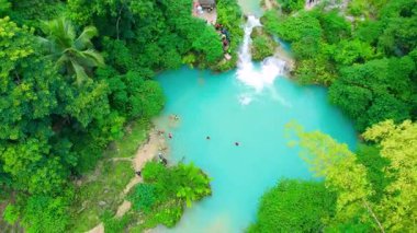 Turkuaz şelale havası ve kalabalık ormanın ortasında yüzen insanlarla dolu temiz havuzlar, Kawasan Şelalesi, Cebu, Filipinler.