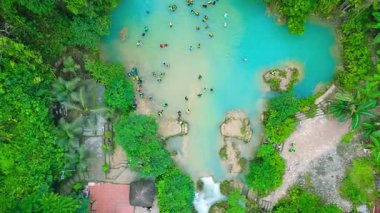 Filipinler 'deki Kawasan Şelalesi' nde yemyeşil orman yapraklarıyla çevrili canlı bir turkuaz şelalesi ve yüzen bir sürü insanla dolu doğal havuzlar..