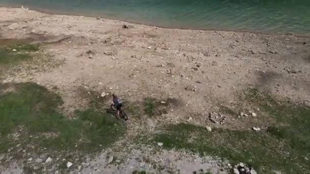 Rowerzysta Górski Nad Jeziorem Jedzie Przejażdżkę Kamienistej Plaży — Wideo stockowe