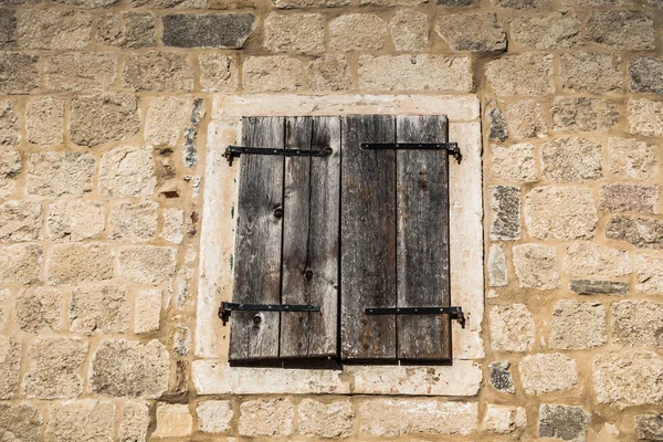 Closed old wooden window on a stone wall
